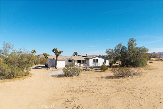 view of front facade with a garage and dirt driveway