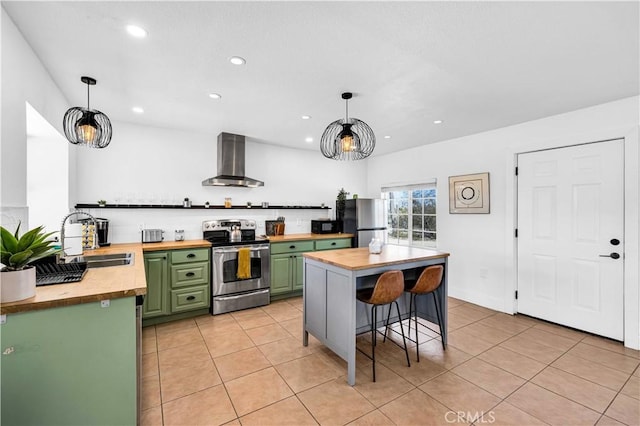 kitchen with green cabinetry, stainless steel appliances, butcher block countertops, and wall chimney exhaust hood