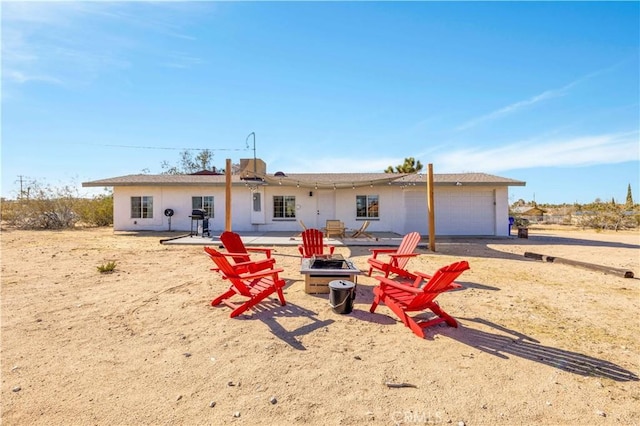 back of property with a patio, a fire pit, and a garage