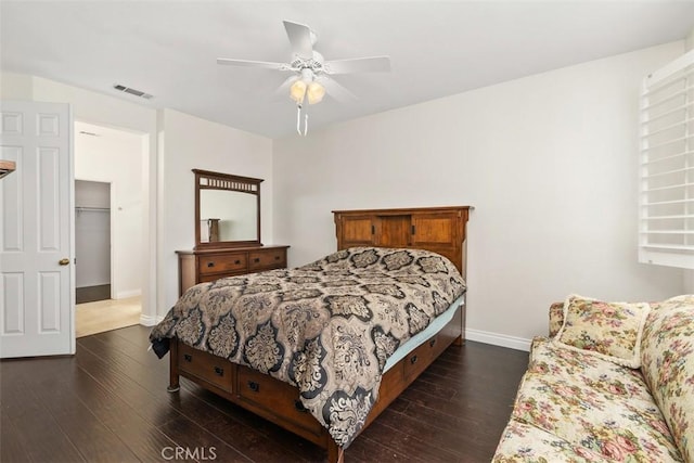 bedroom with dark wood-style floors, visible vents, a ceiling fan, and baseboards