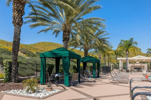 surrounding community with a mountain view, fence, and a pergola