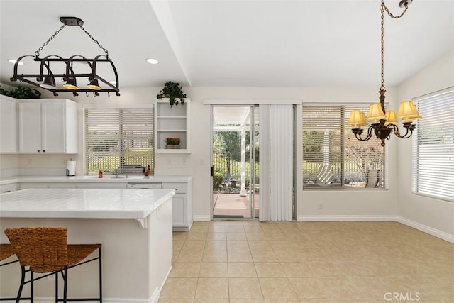 kitchen featuring tile countertops, light tile patterned floors, recessed lighting, white cabinets, and a chandelier