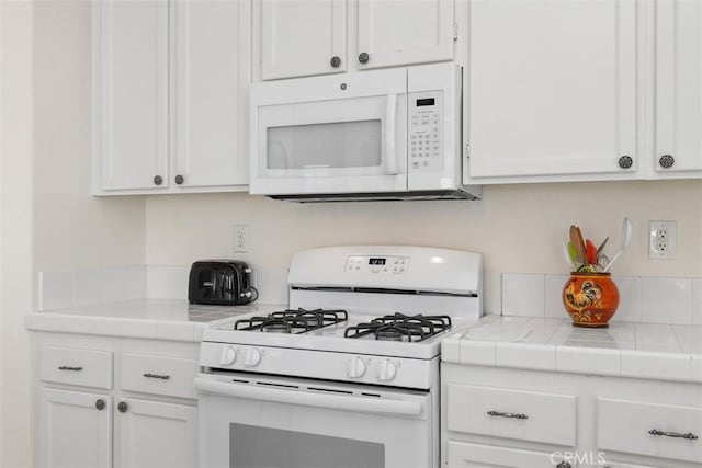 kitchen with white appliances, tile counters, and white cabinets