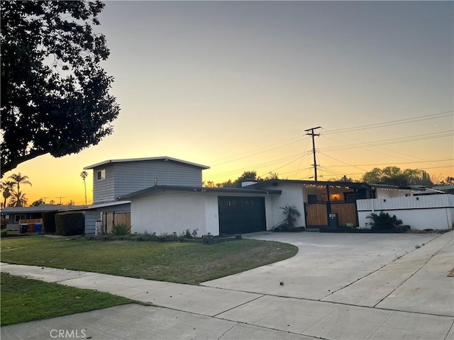 view of front of property with an attached garage, fence, stucco siding, a yard, and driveway