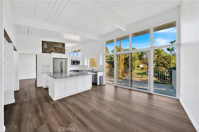 kitchen featuring dark wood-type flooring, white cabinets, a kitchen island, stainless steel appliances, and beam ceiling