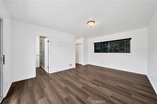 unfurnished bedroom featuring a closet, baseboards, connected bathroom, and dark wood finished floors