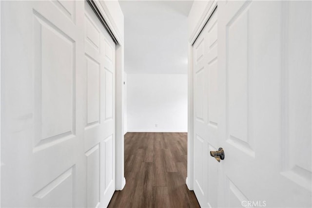 corridor featuring baseboards and dark wood-style floors