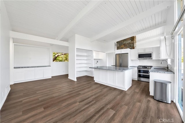 kitchen featuring open floor plan, white cabinetry, a kitchen island, stainless steel appliances, and vaulted ceiling with beams