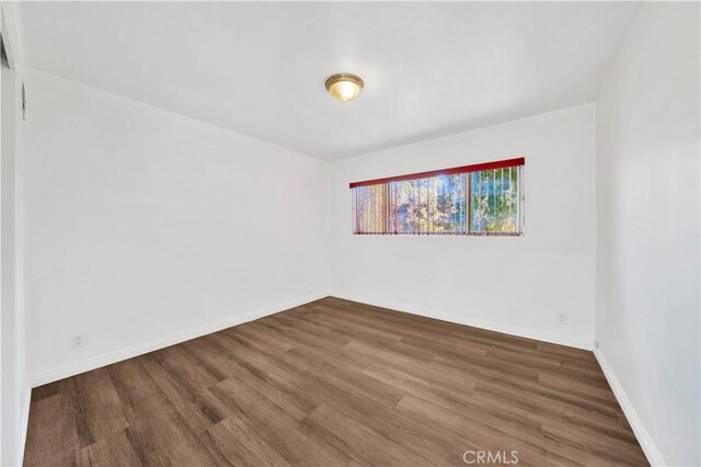 empty room with baseboards and wood finished floors