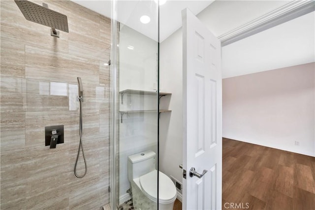 full bathroom with toilet, a tile shower, and wood finished floors