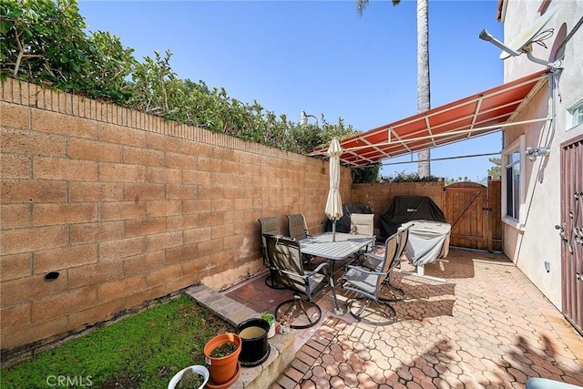 view of patio / terrace with outdoor dining area, area for grilling, a gate, and a fenced backyard