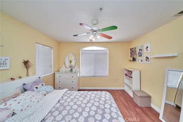 bedroom featuring visible vents, a ceiling fan, baseboards, and wood finished floors