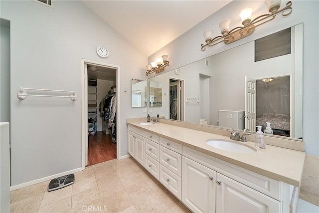 bathroom with double vanity, tile patterned flooring, lofted ceiling, and a sink