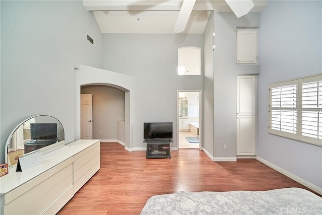 living room featuring arched walkways, visible vents, baseboards, and light wood-style floors