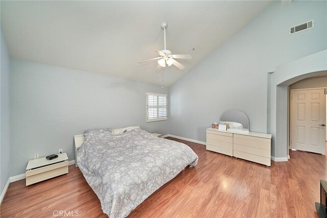 bedroom with arched walkways, visible vents, baseboards, and wood finished floors