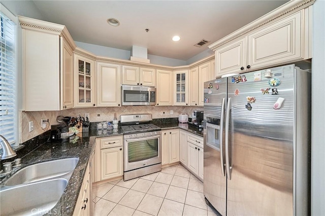 kitchen with visible vents, a sink, cream cabinets, appliances with stainless steel finishes, and light tile patterned floors