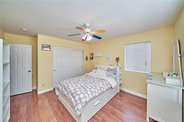 bedroom featuring a closet, baseboards, wood finished floors, and a ceiling fan