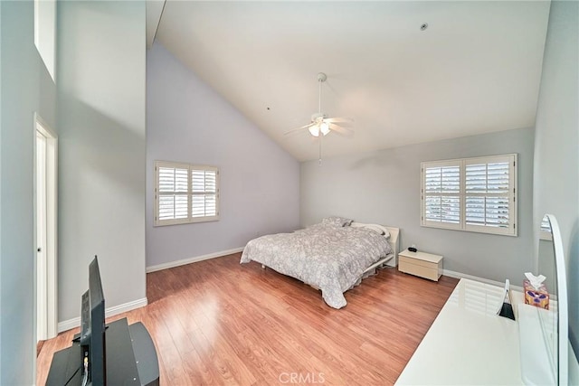 bedroom with multiple windows, wood finished floors, baseboards, and high vaulted ceiling