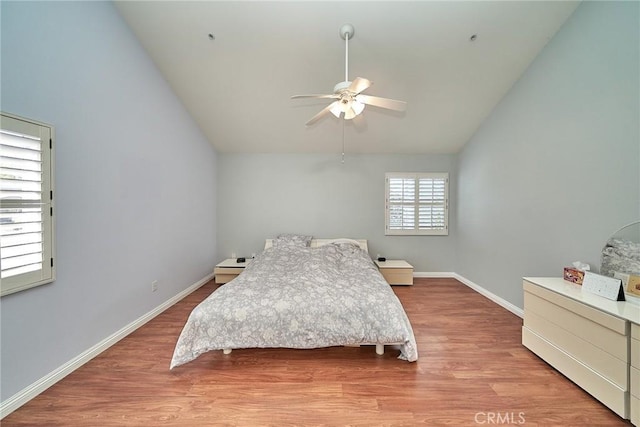 bedroom with a ceiling fan, wood finished floors, baseboards, and high vaulted ceiling