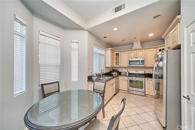 kitchen featuring visible vents, light tile patterned flooring, a sink, appliances with stainless steel finishes, and dark countertops