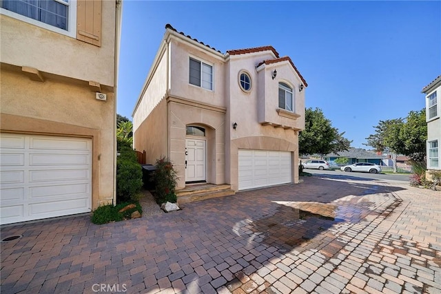 view of front facade featuring decorative driveway, an attached garage, and stucco siding