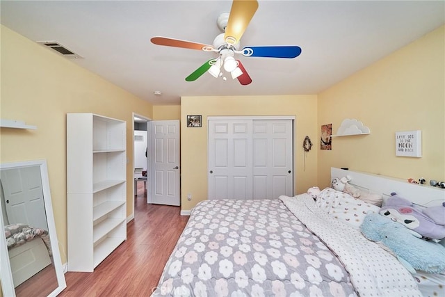 bedroom featuring visible vents, a ceiling fan, wood finished floors, a closet, and baseboards