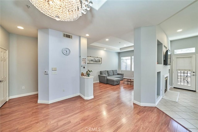 interior space with a tray ceiling, recessed lighting, visible vents, and light wood finished floors