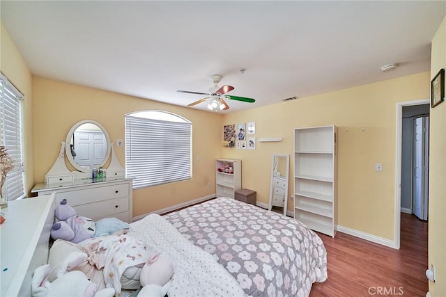 bedroom with visible vents, multiple windows, baseboards, and wood finished floors