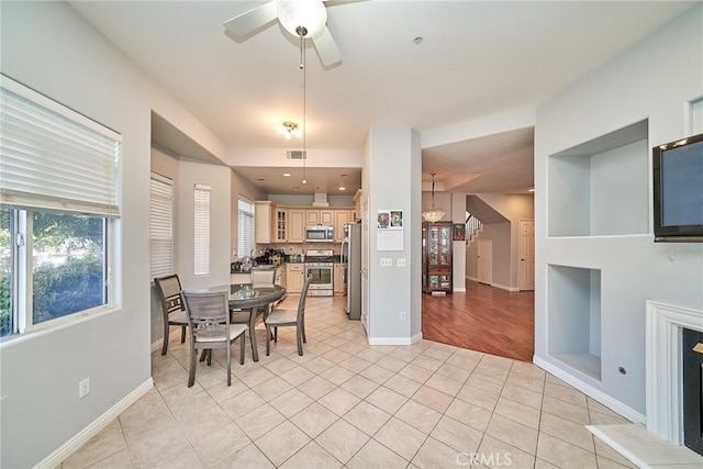 dining room featuring light tile patterned floors, baseboards, and ceiling fan with notable chandelier