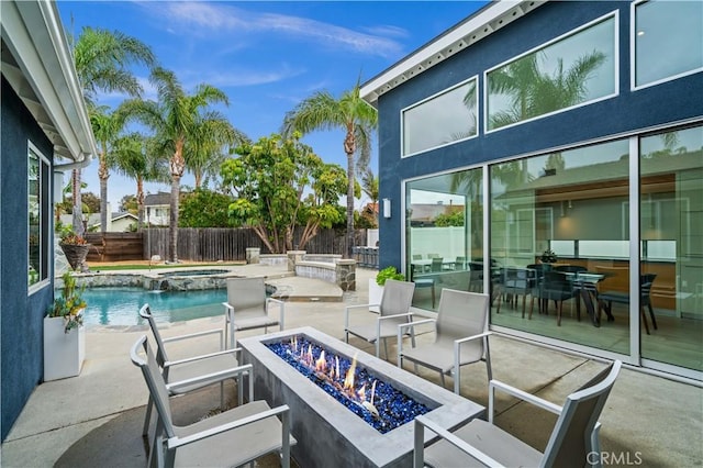 view of patio featuring a pool with connected hot tub, a fenced backyard, and an outdoor fire pit