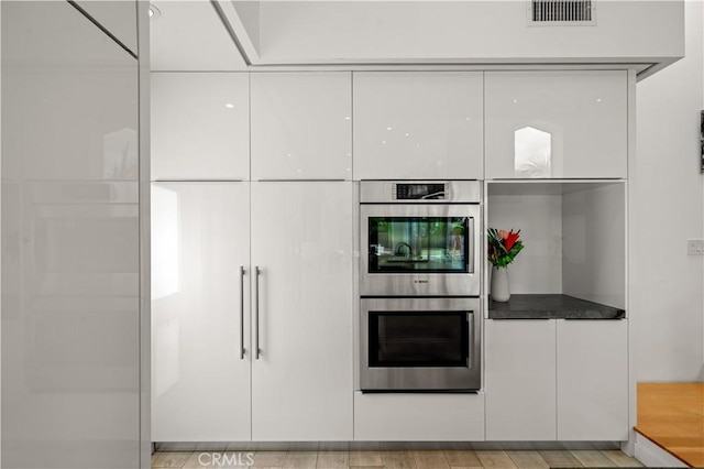 kitchen featuring white cabinetry, modern cabinets, visible vents, and stainless steel double oven