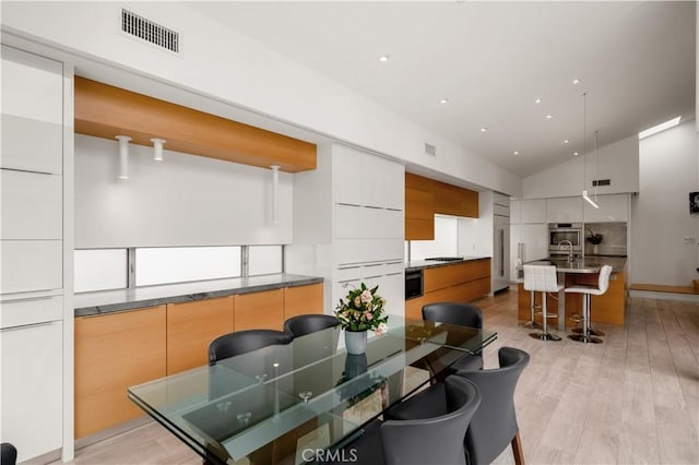 dining area with recessed lighting, visible vents, high vaulted ceiling, and light wood finished floors