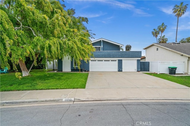 view of front of property featuring a front lawn, concrete driveway, and fence