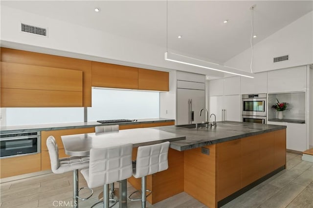 kitchen with dark countertops, modern cabinets, visible vents, and appliances with stainless steel finishes