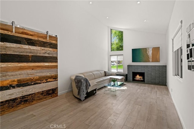 living area featuring a fireplace with flush hearth, high vaulted ceiling, baseboards, and wood finished floors