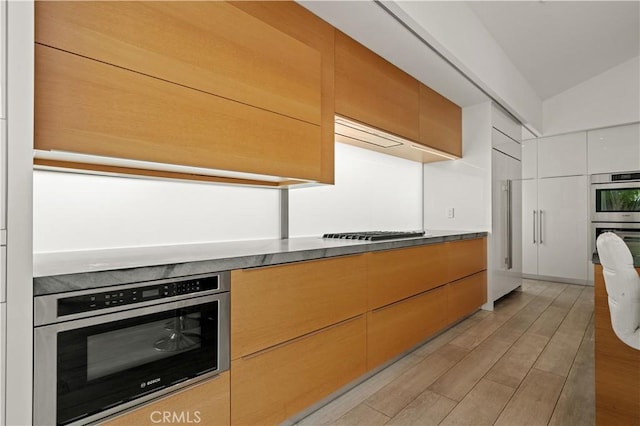 kitchen featuring gas stovetop, stainless steel double oven, modern cabinets, and light wood-style floors