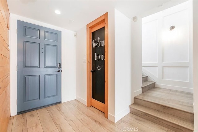 entrance foyer with recessed lighting, light wood-style flooring, stairs, and baseboards