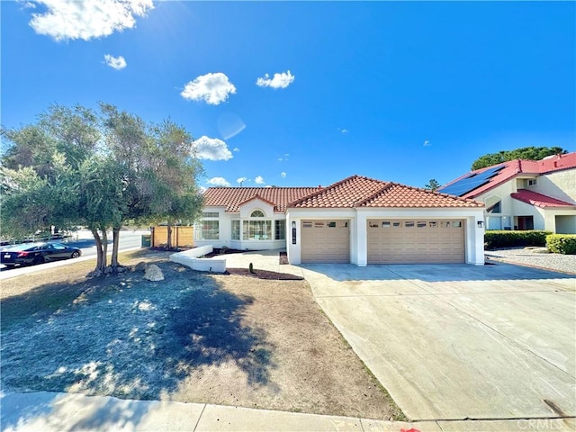 mediterranean / spanish-style house with stucco siding, a tiled roof, an attached garage, and concrete driveway