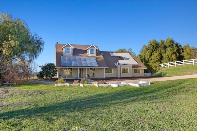 view of front of property with a front lawn, fence, and roof mounted solar panels