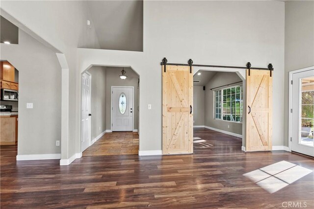 foyer featuring a barn door, a high ceiling, and wood finished floors