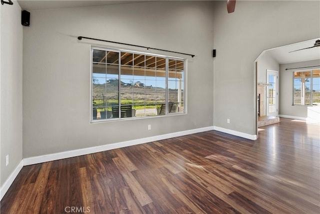 unfurnished room with vaulted ceiling, baseboards, and wood finished floors