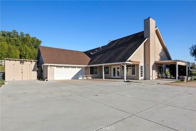 view of front of house with concrete driveway, a chimney, and a garage