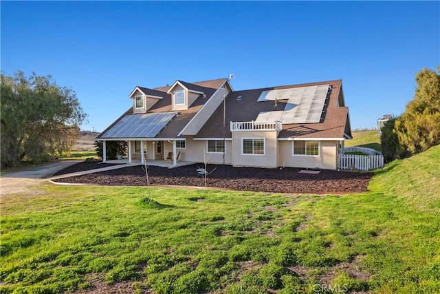 back of property with a yard, roof mounted solar panels, a patio area, and fence