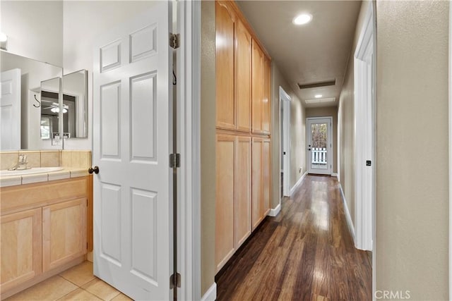 hallway with wood finished floors, baseboards, attic access, recessed lighting, and a sink