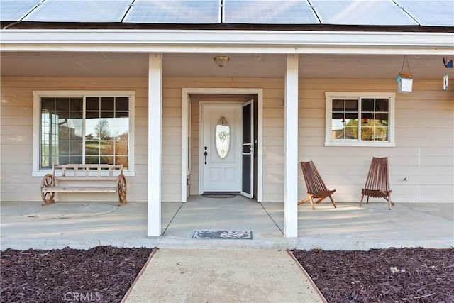 view of exterior entry with solar panels and a porch