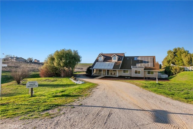 view of front of property with roof mounted solar panels, a front yard, and driveway