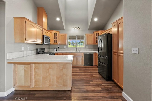 kitchen featuring stainless steel appliances, glass insert cabinets, a peninsula, and light brown cabinets