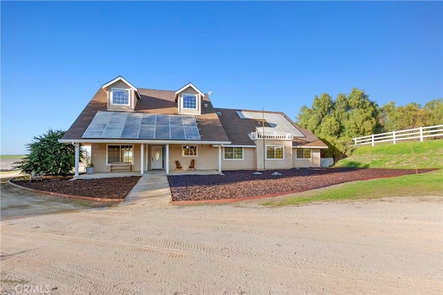 view of front of property with solar panels, a porch, and fence