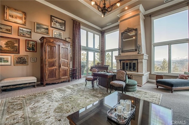 sitting room with a towering ceiling, a fireplace, carpet flooring, and crown molding