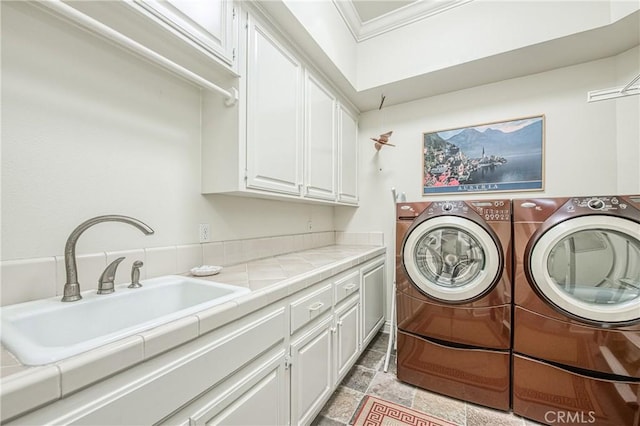 washroom featuring cabinet space, a sink, stone finish floor, washer and dryer, and crown molding